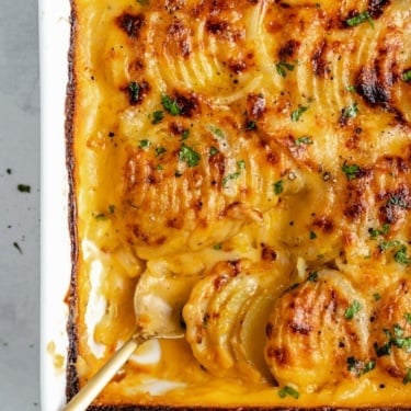 creamy au gratin potatoes in a baking dish with a spoon