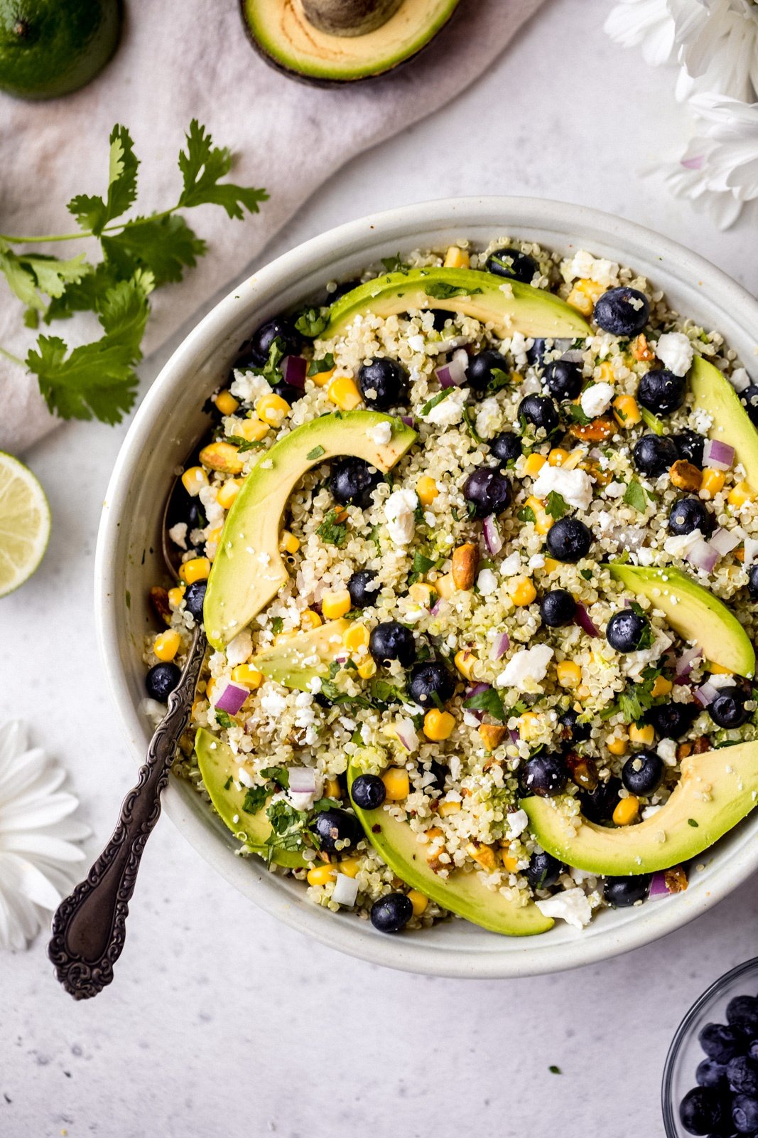 avocado blueberry quinoa salad in a bowl with a spoon on the left side of the bowl