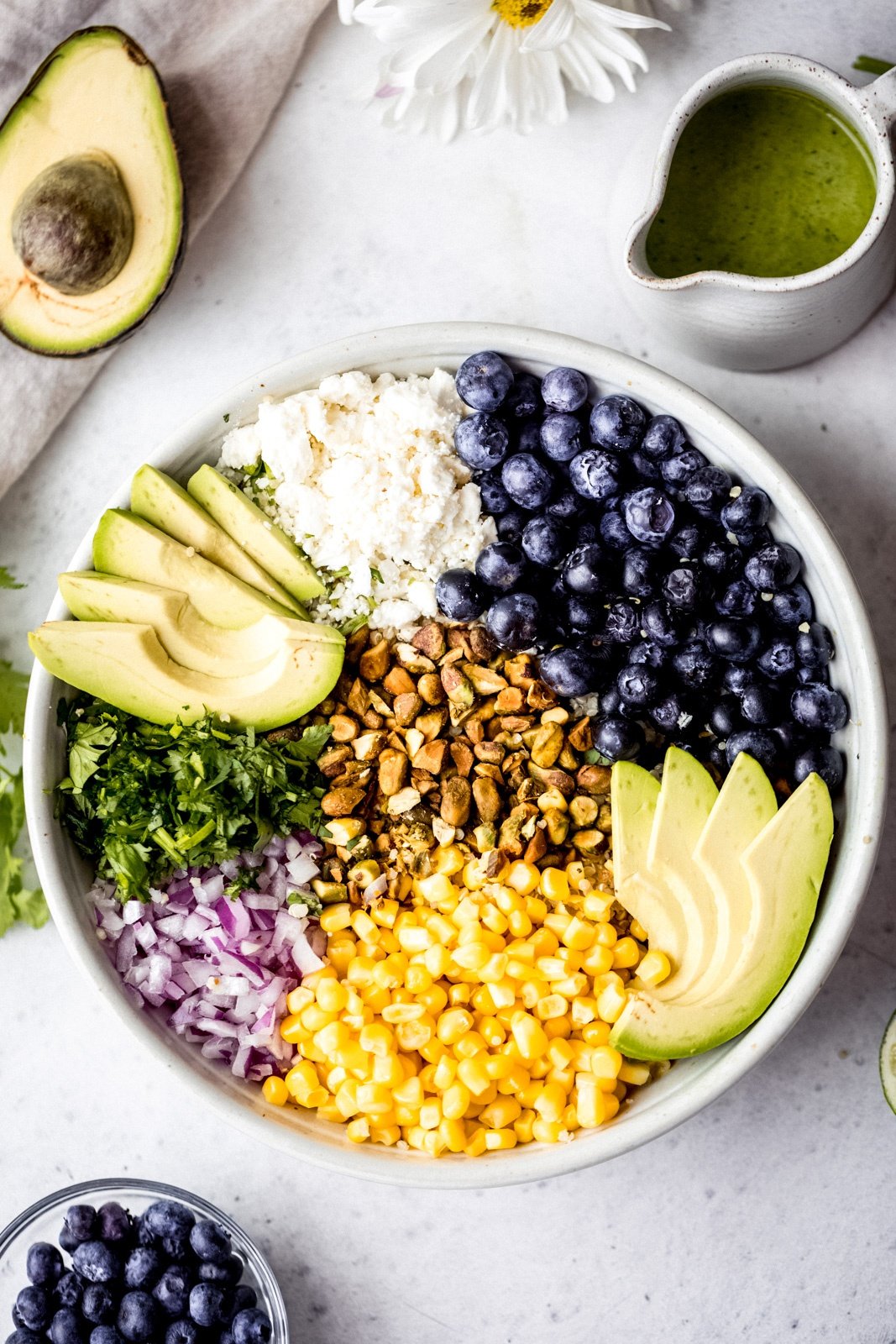 corn, blueberries, quinoa, feta, avocado, red onion, pistachios and cilantro in a bowl