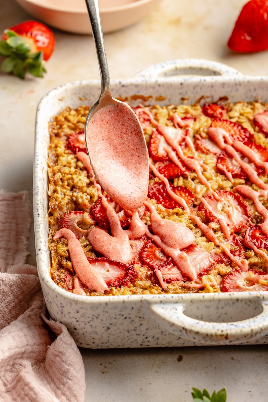 drizzling strawberry glaze onto a strawberry oatmeal bake