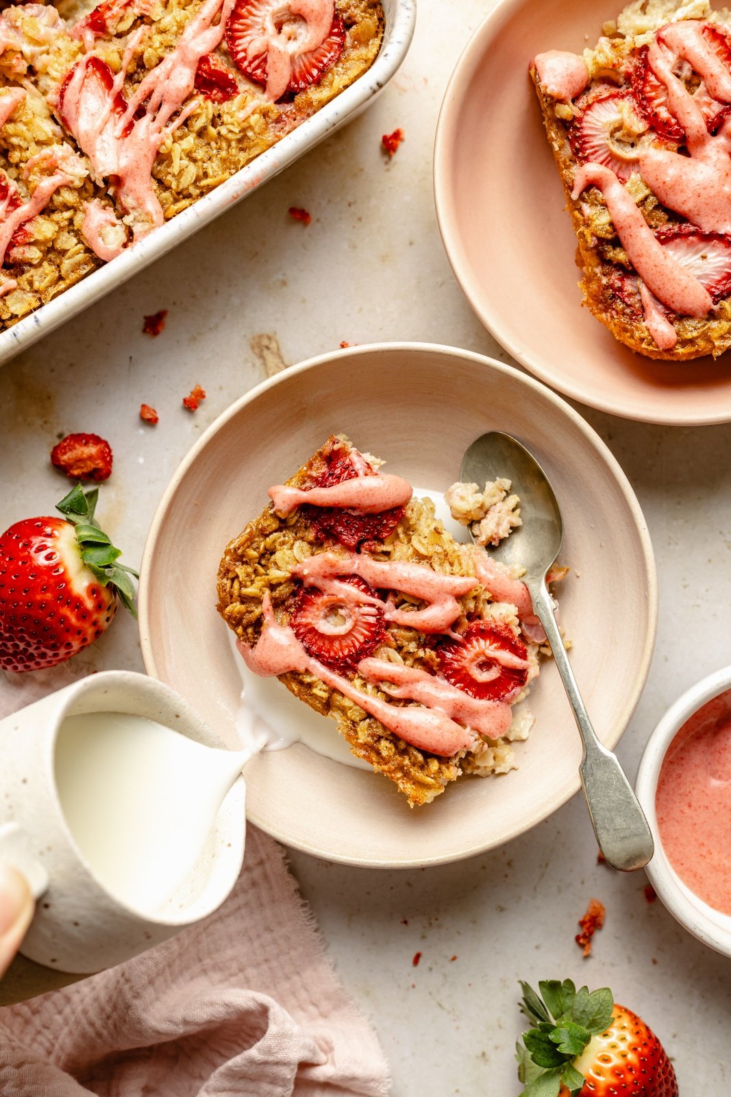 pouring milk over a slice of strawberry baked oatmeal