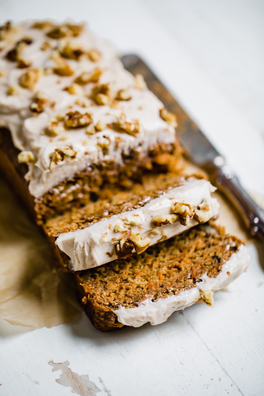 healthier carrot cake banana bread loaf on a white board with two slices cut out