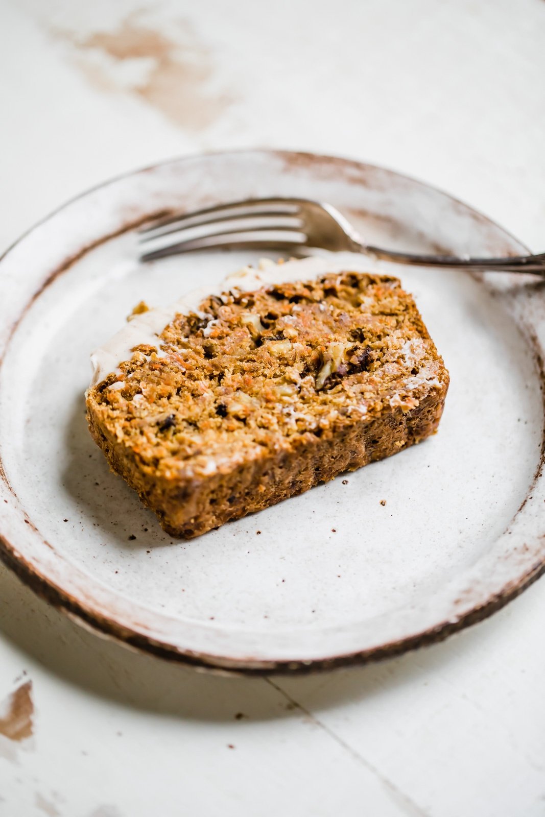 one slice of carrot cake banana bread on a plate with a fork next to it