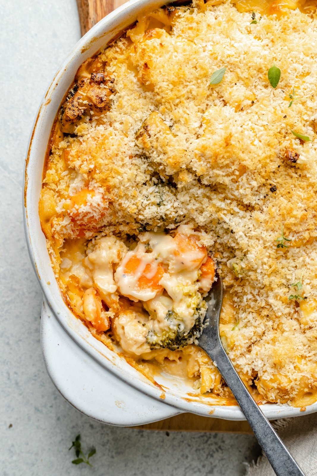 scooping cheddar broccoli cauliflower gratin out of a skillet