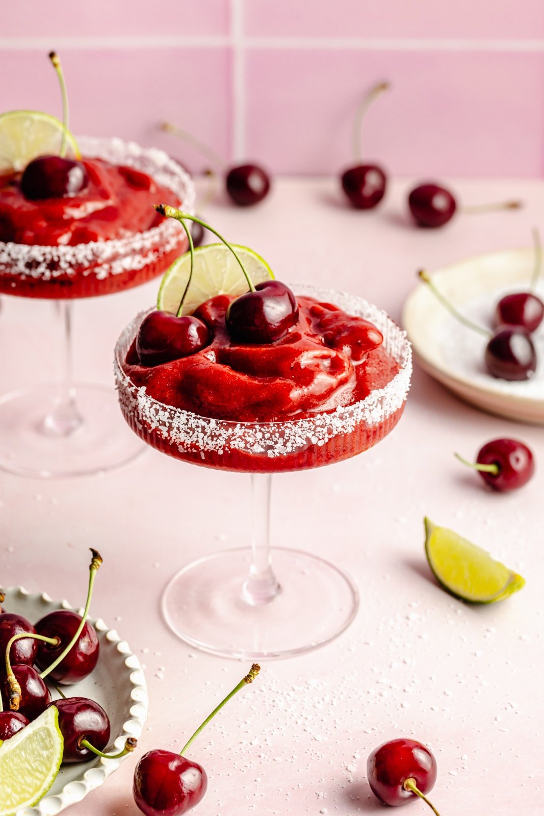 easy frozen cherry margarita in a glass topped with fresh cherries