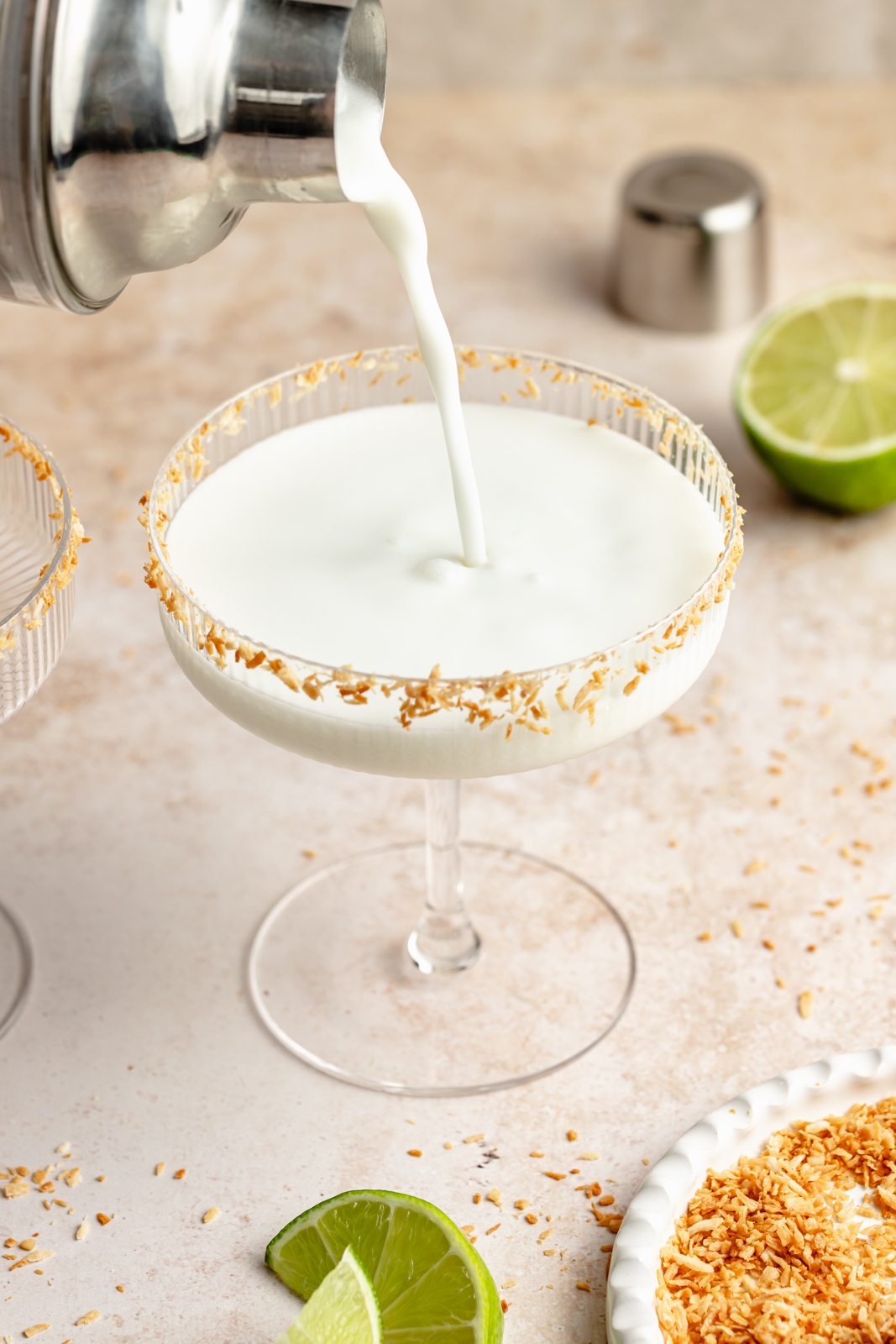 pouring a coconut margarita into a cocktail glass