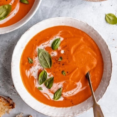 easy vegan tomato soup in a bowl topped with basil leaves