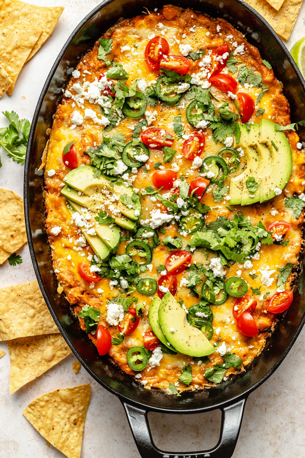 southwest bean dip in a skillet topped with avocado and cilantro