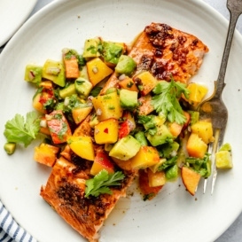 firecracker salmon on a plate topped with peach salsa