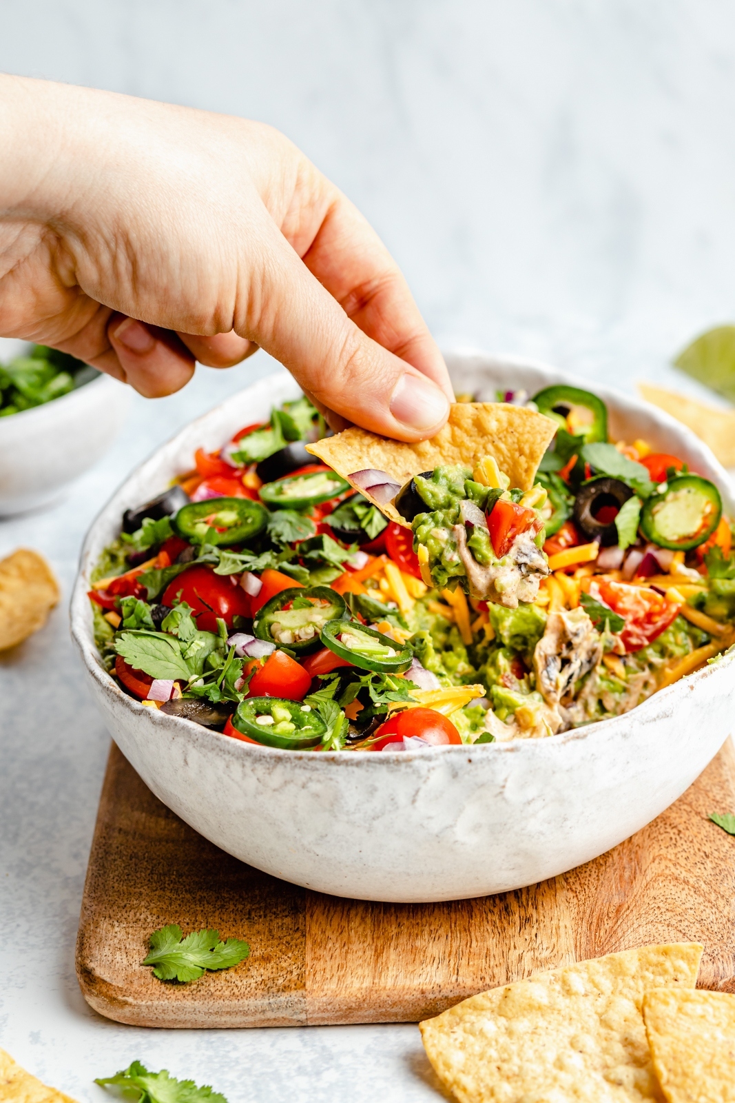 scooping healthy 7 layer dip out of a serving bowl