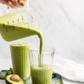 pouring a green smoothie into a glass