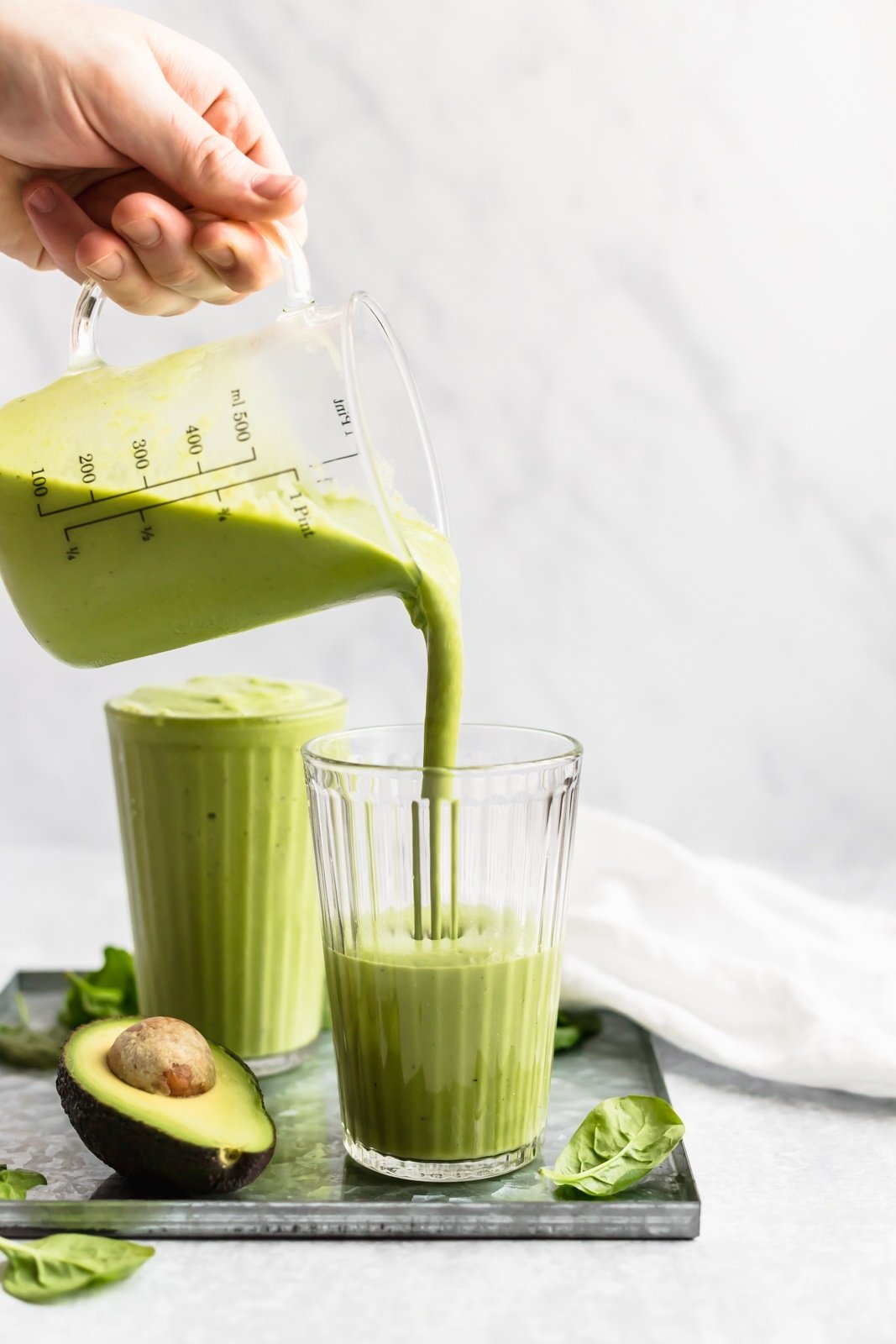 green smoothie being poured into a glass