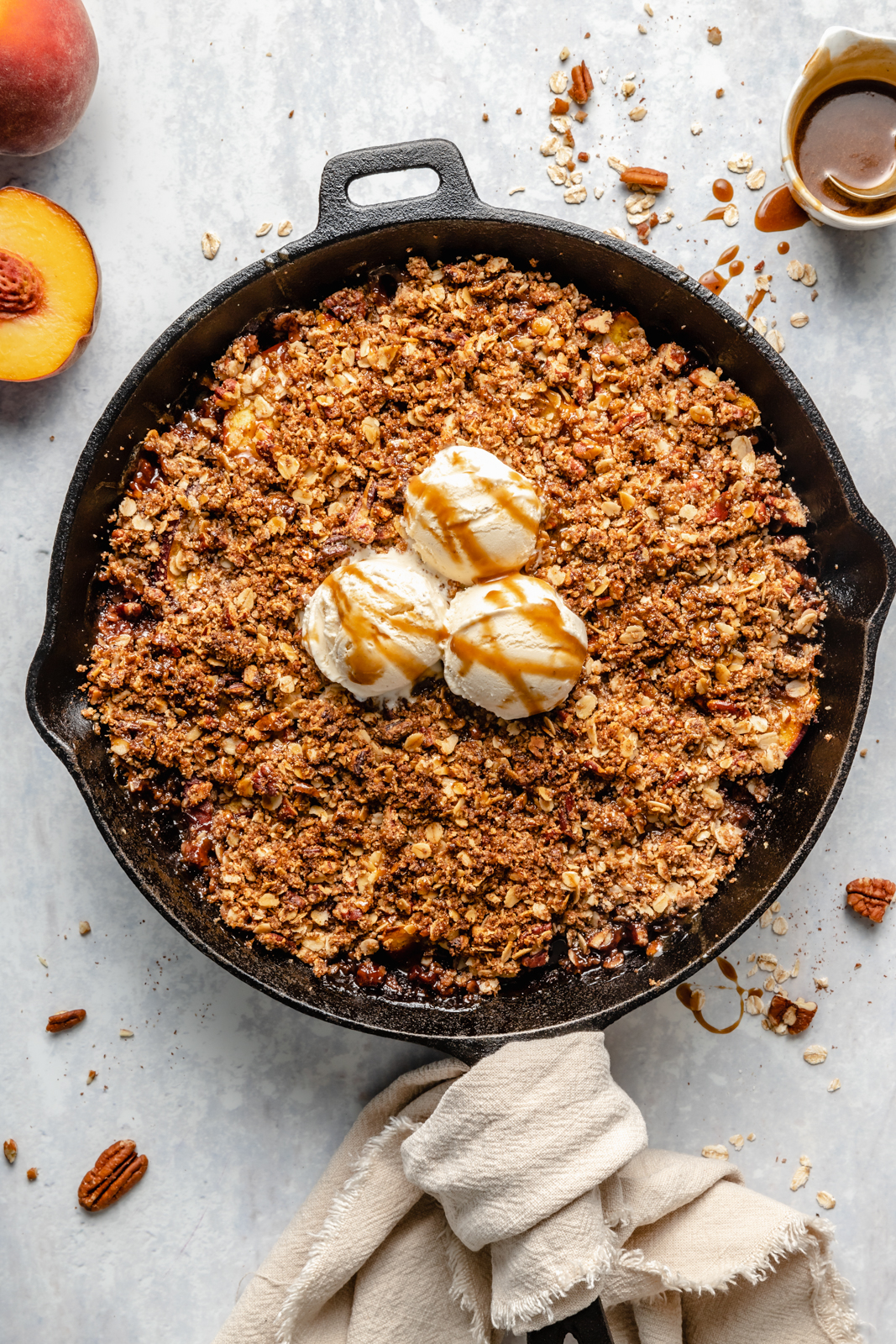 healthy peach crisp in a skillet topped with ice cream