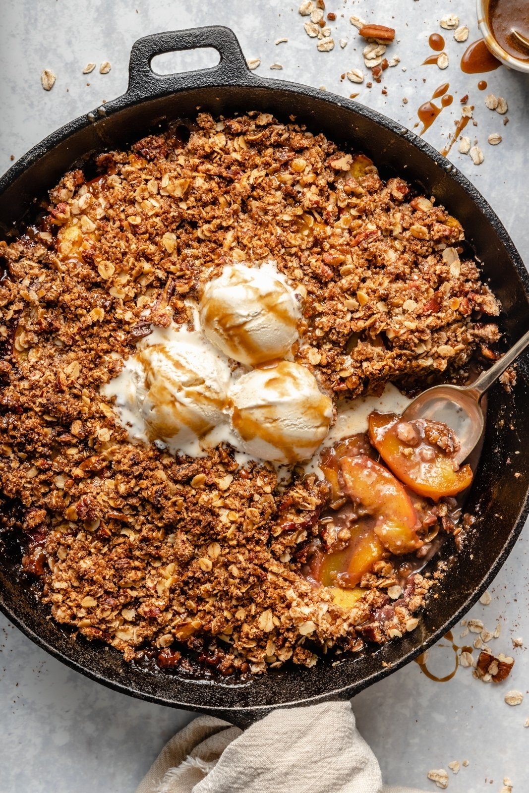 healthy peach crisp in a skillet topped with ice cream