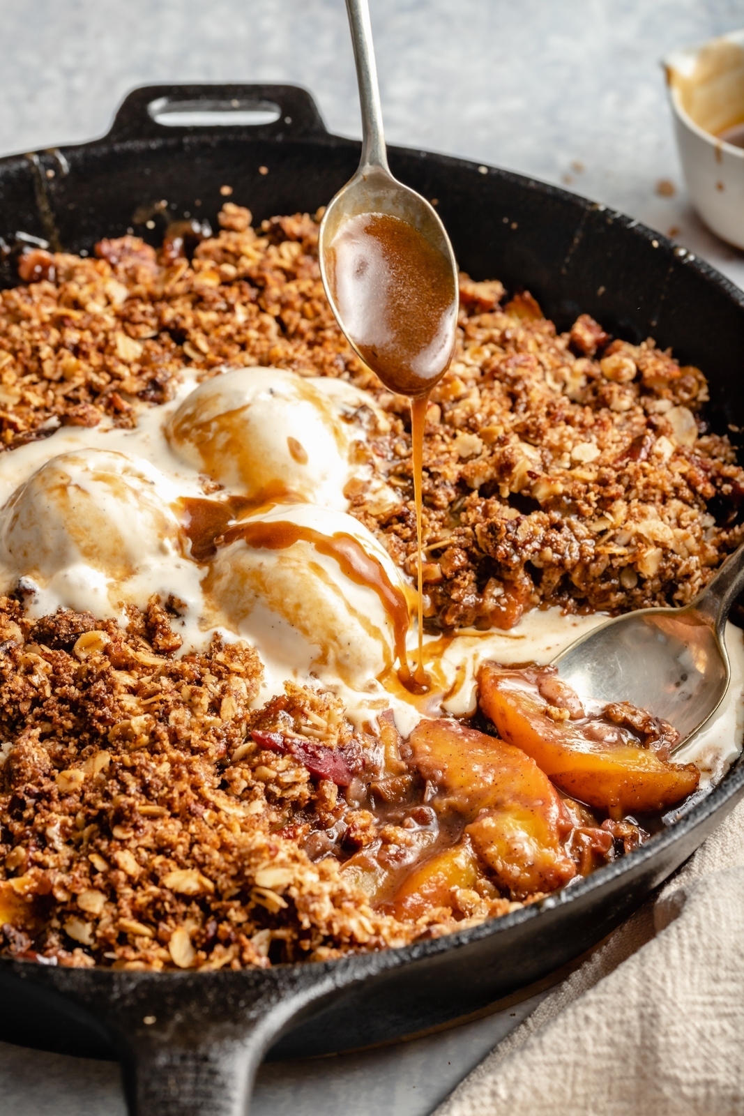 drizzling caramel onto a peach crisp in a skillet