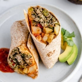 green chile chicken burrito on a plate with avocado