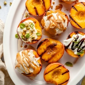 grilled peaches on a platter with different toppings