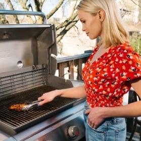 blonde woman grilling chicken breast