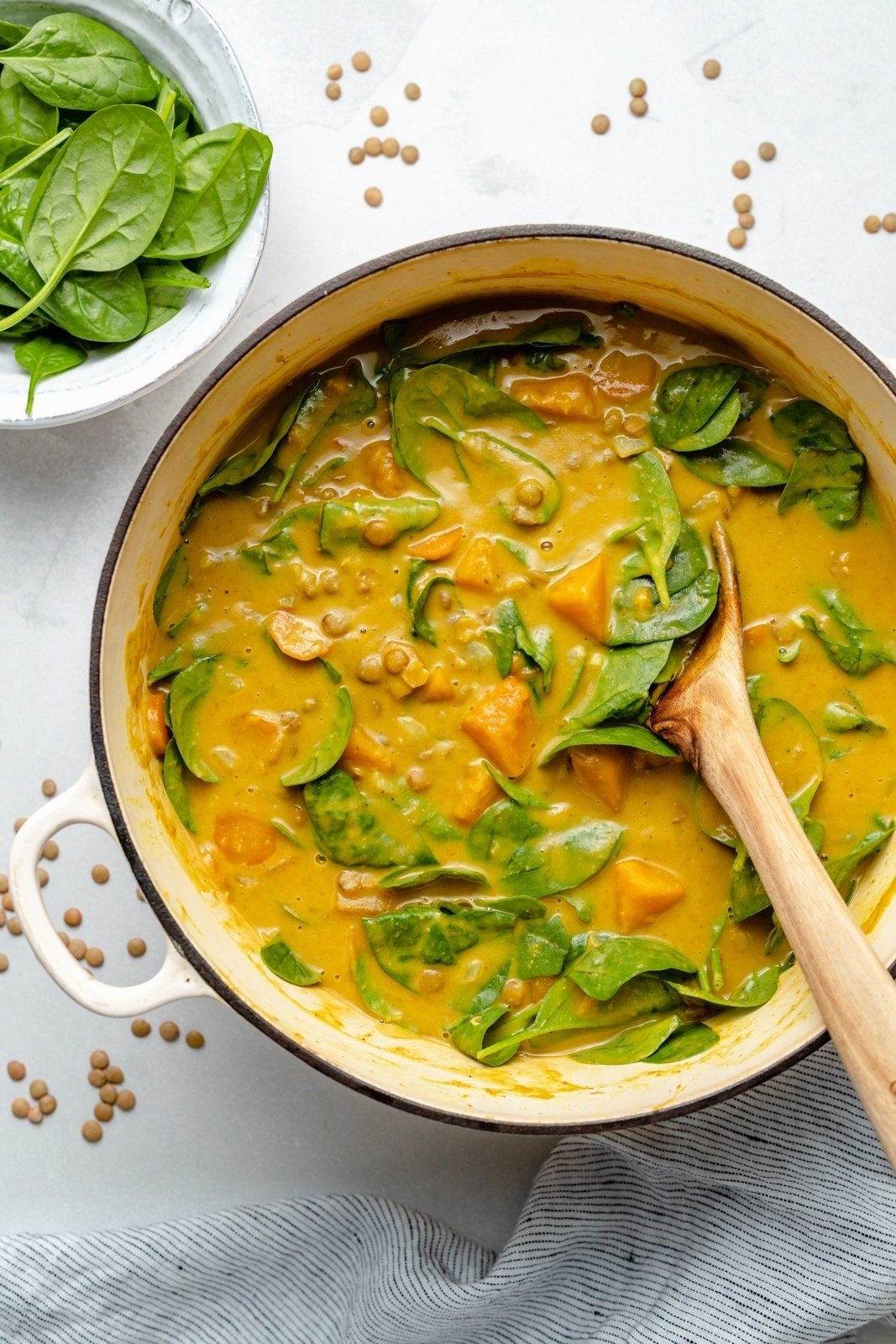 vegan butternut squash lentil soup in a pot with spinach