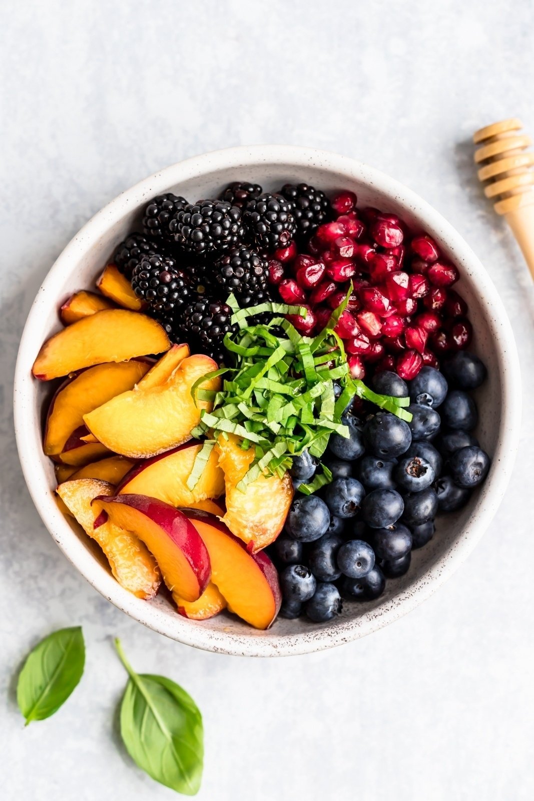 summer peach fruit salad ingredients in a bowl with basil ribbons on top