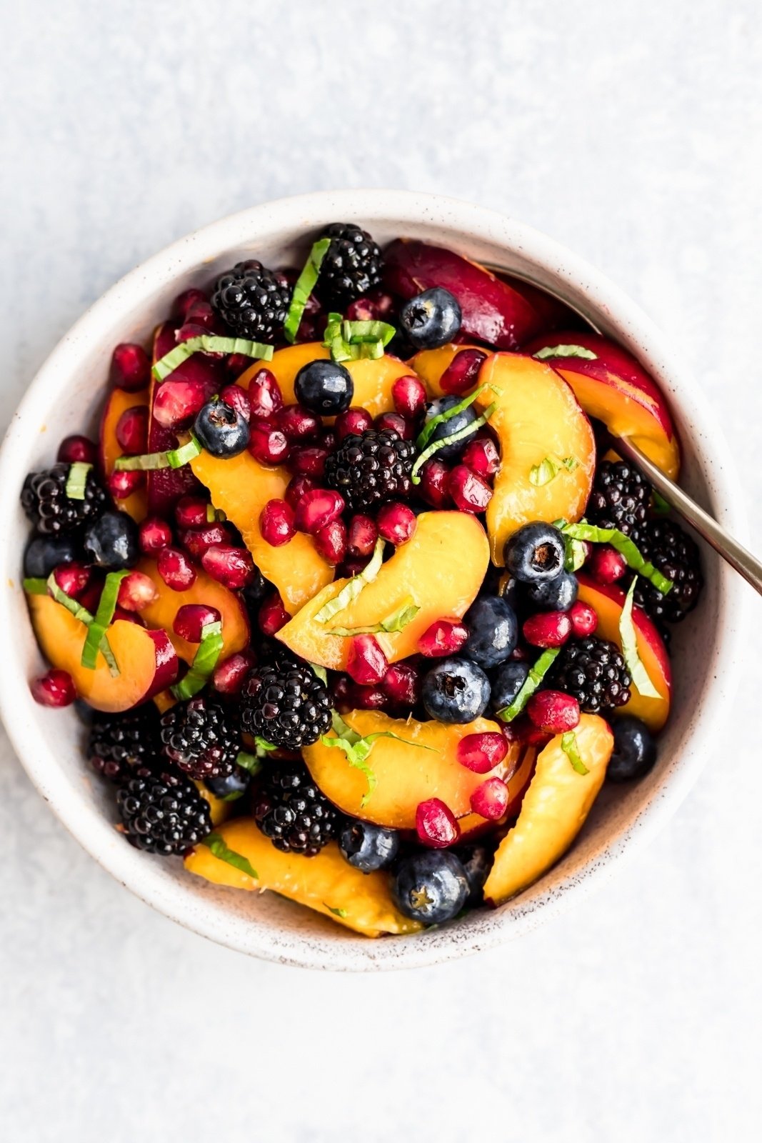 summer peach fruit salad in a bowl with basil ribbons