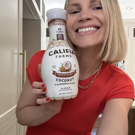 Monique from Ambitious Kitchen holding a bottle of non-dairy milk