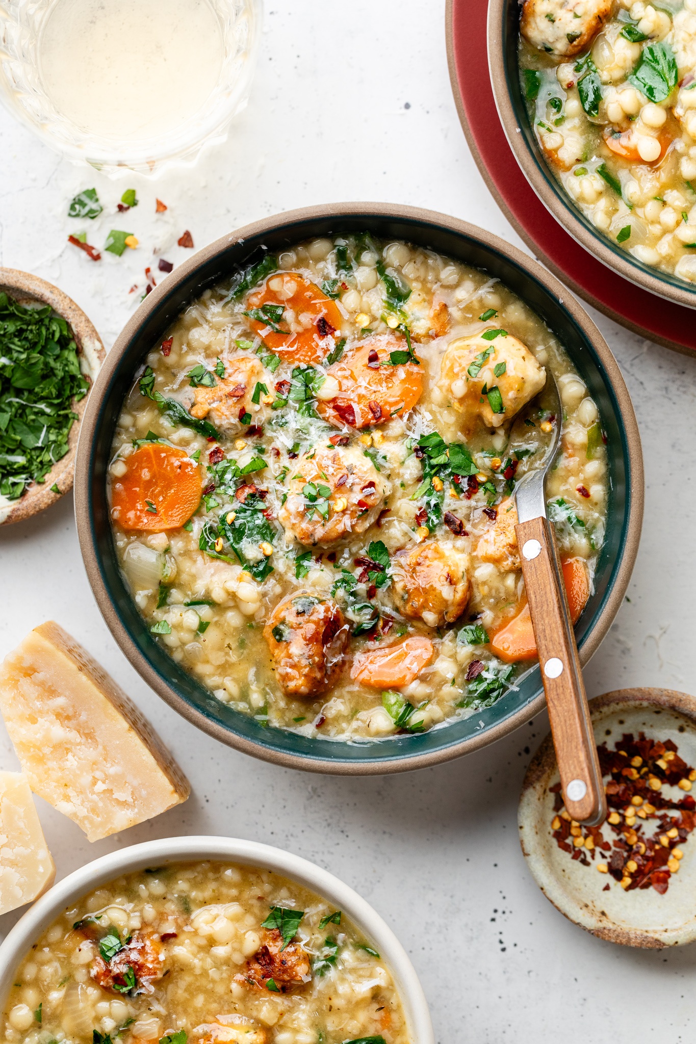 Italian wedding soup in bowls next to a parmesan rind