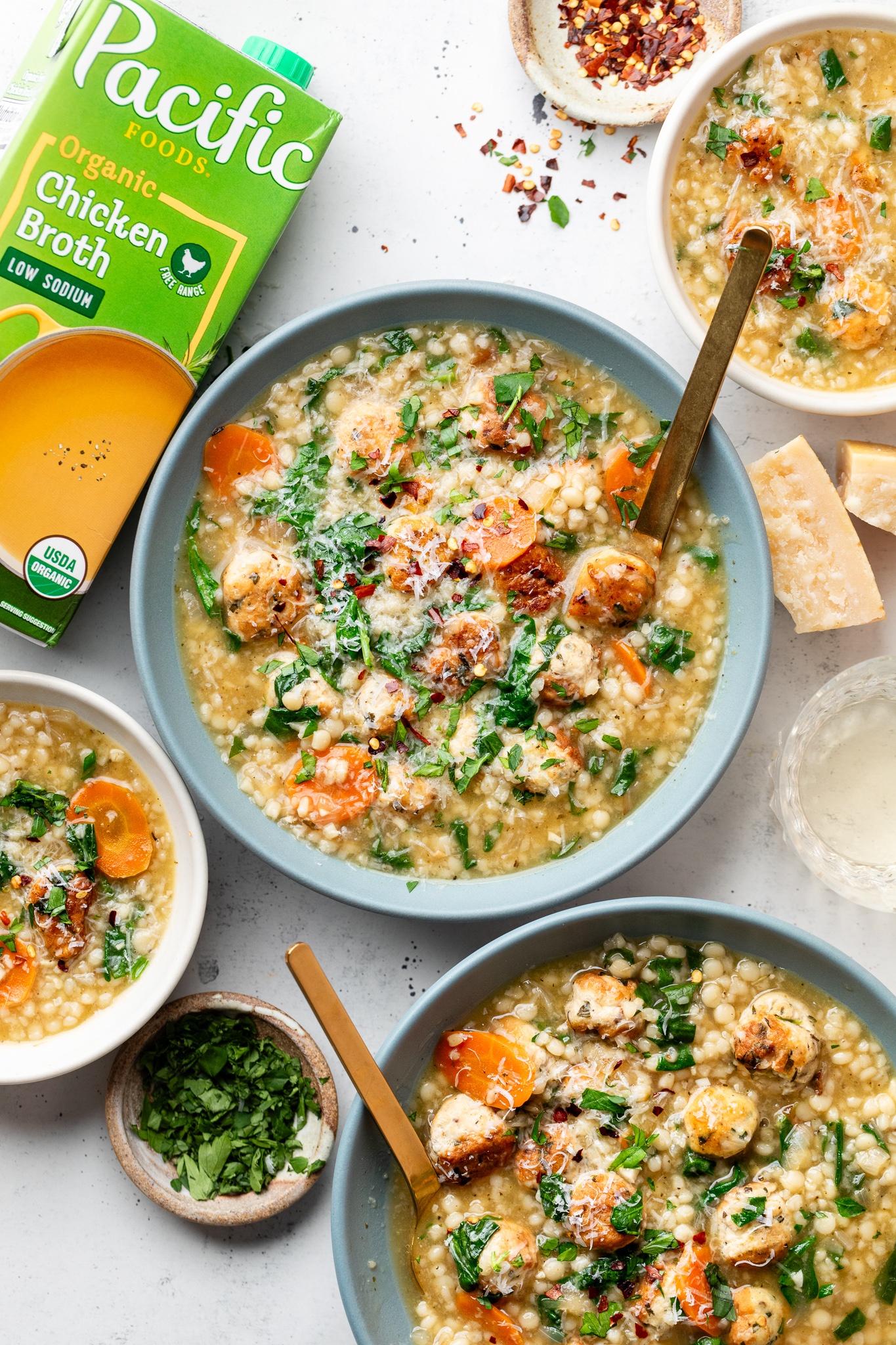 Italian wedding soup in bowls next to a box of chicken broth