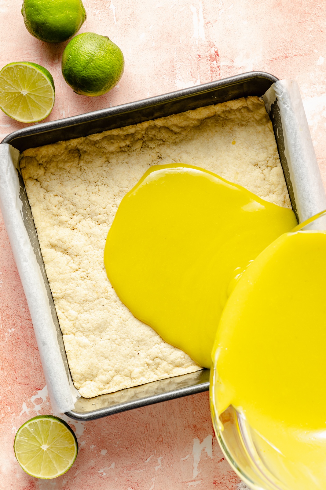 pouring the filling for lime bars onto the crust in a pan