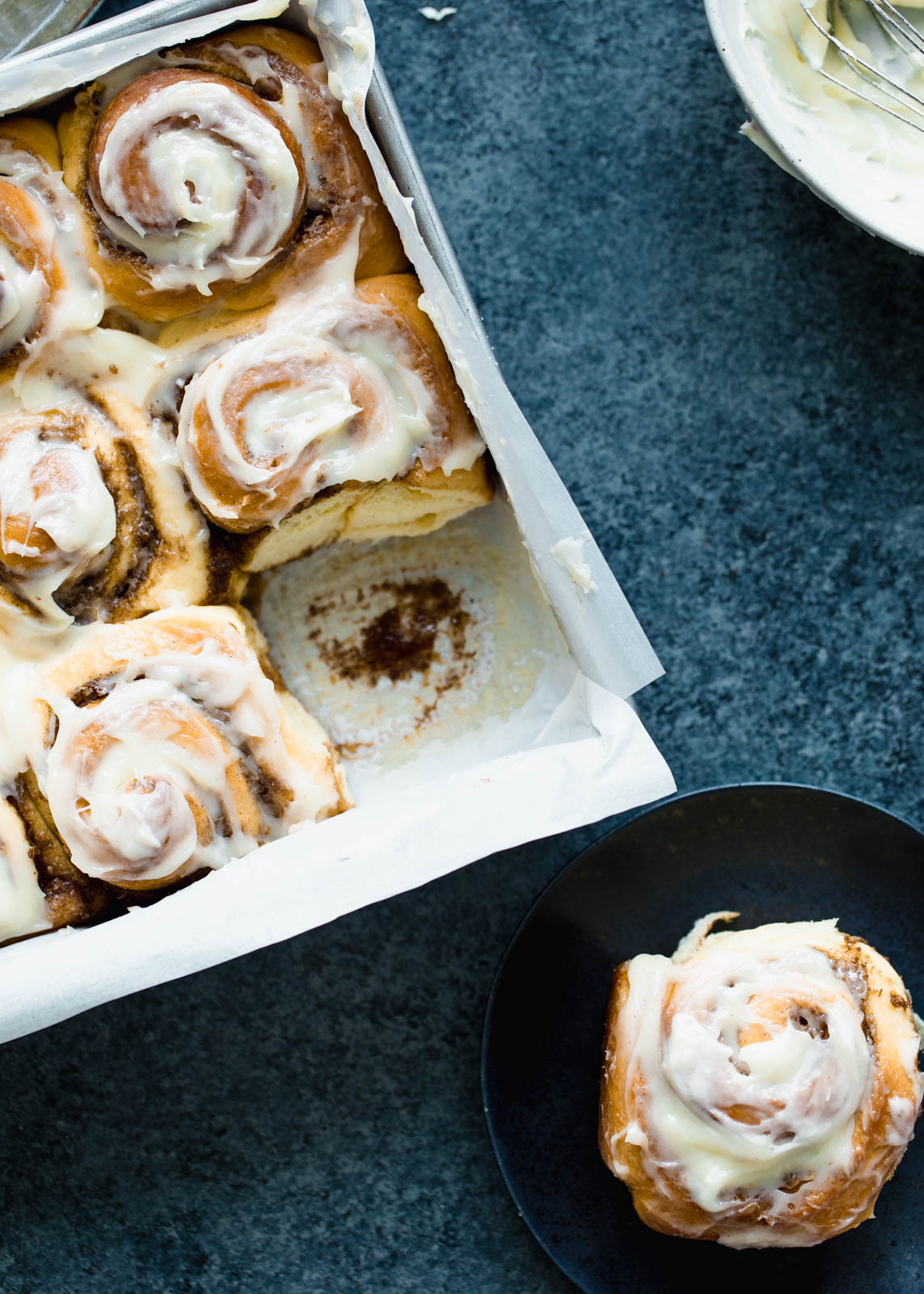 the best cinnamon rolls in a baking pan and on a plate