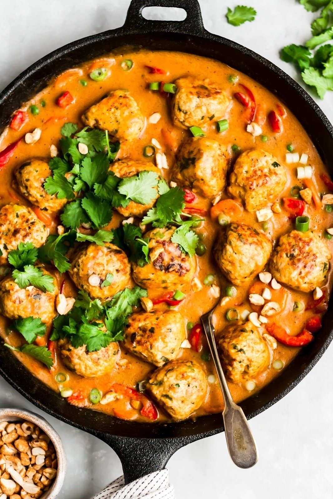 ginger chicken meatballs in a skillet pan with peanut sauce