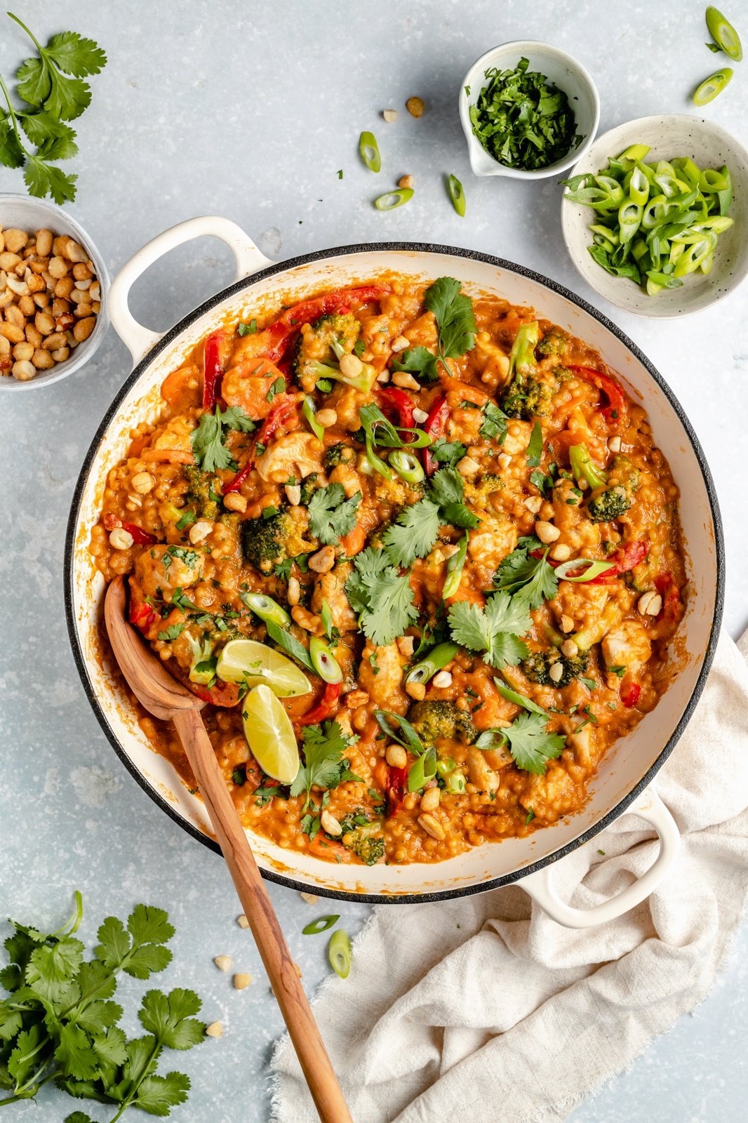 Thai chicken couscous in a pot with a wooden spoon topped with cilantro