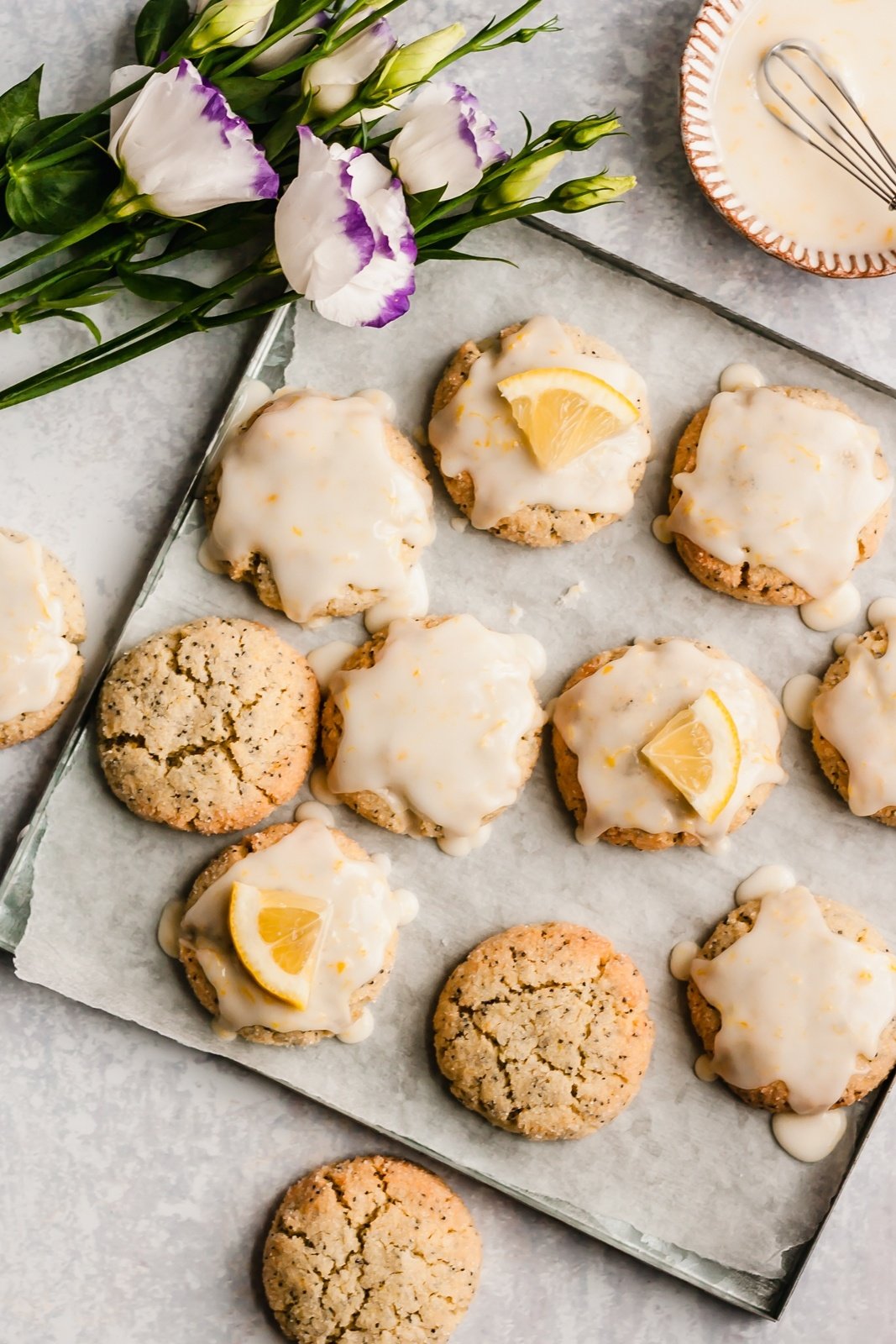 gluten free lemon cookies on a baking tray next to a bunch of flowers