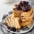 paleo banana coconut flour pancakes in a stack topped with blueberry maple syrup