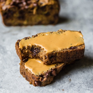 two slices of grain free peanut butter zucchini bread stacked on top of each other and spread with peanut butter