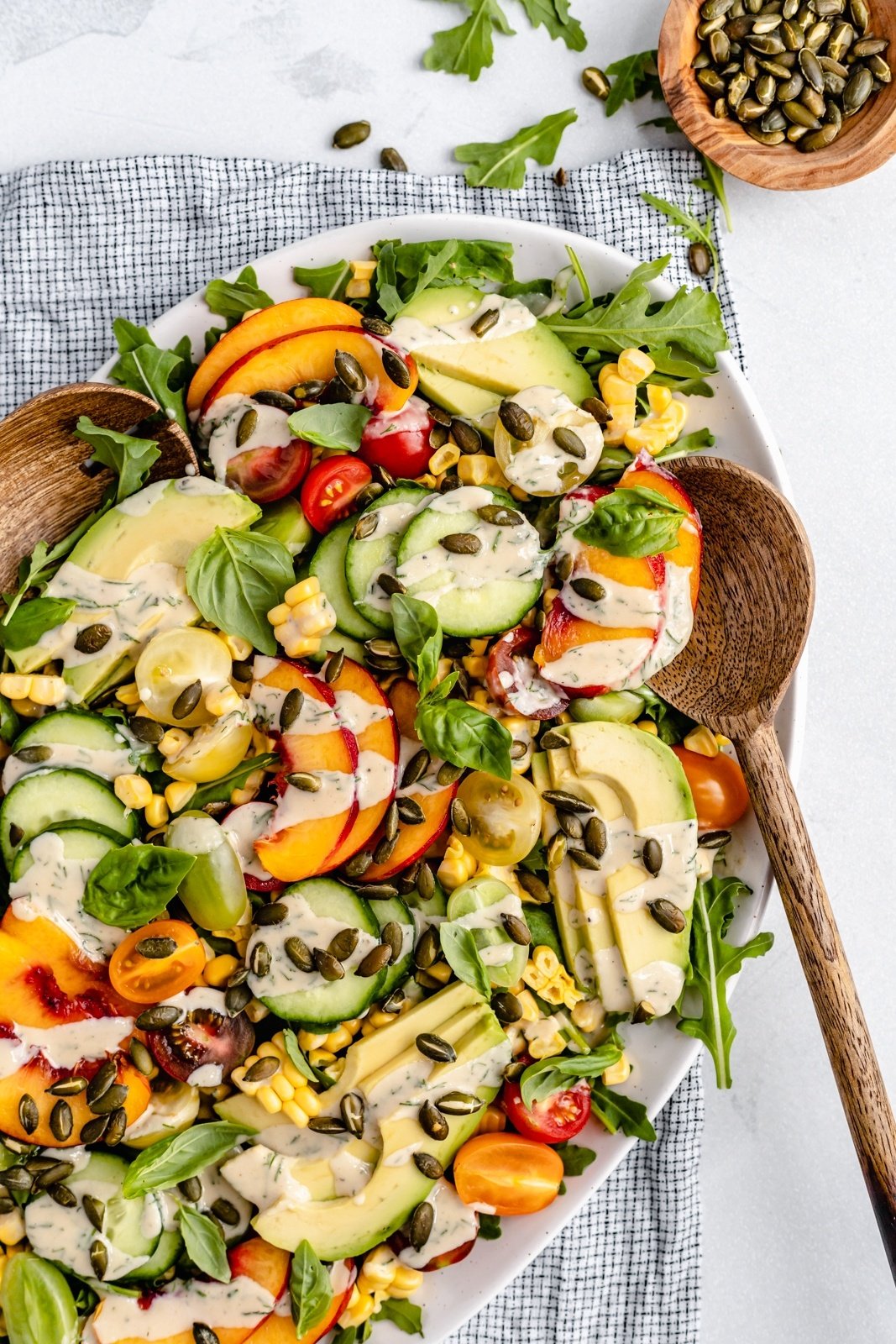 vegan peach tomato salad on a platter with tahini dressing