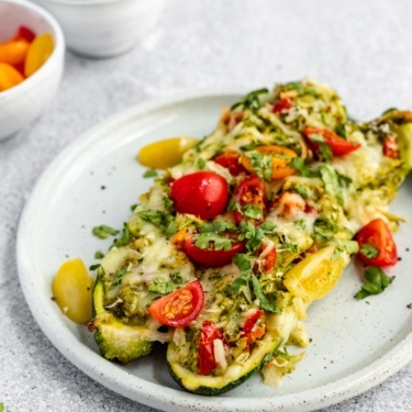 two low carb pesto chicken stuffed zucchini boats on a plate