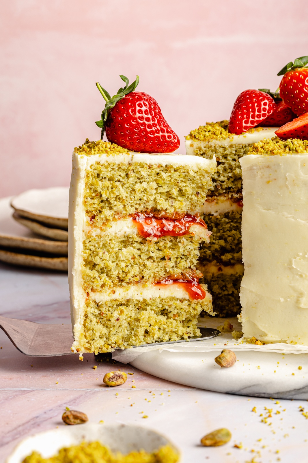 lemon pistachio cake with a slice being pulled out