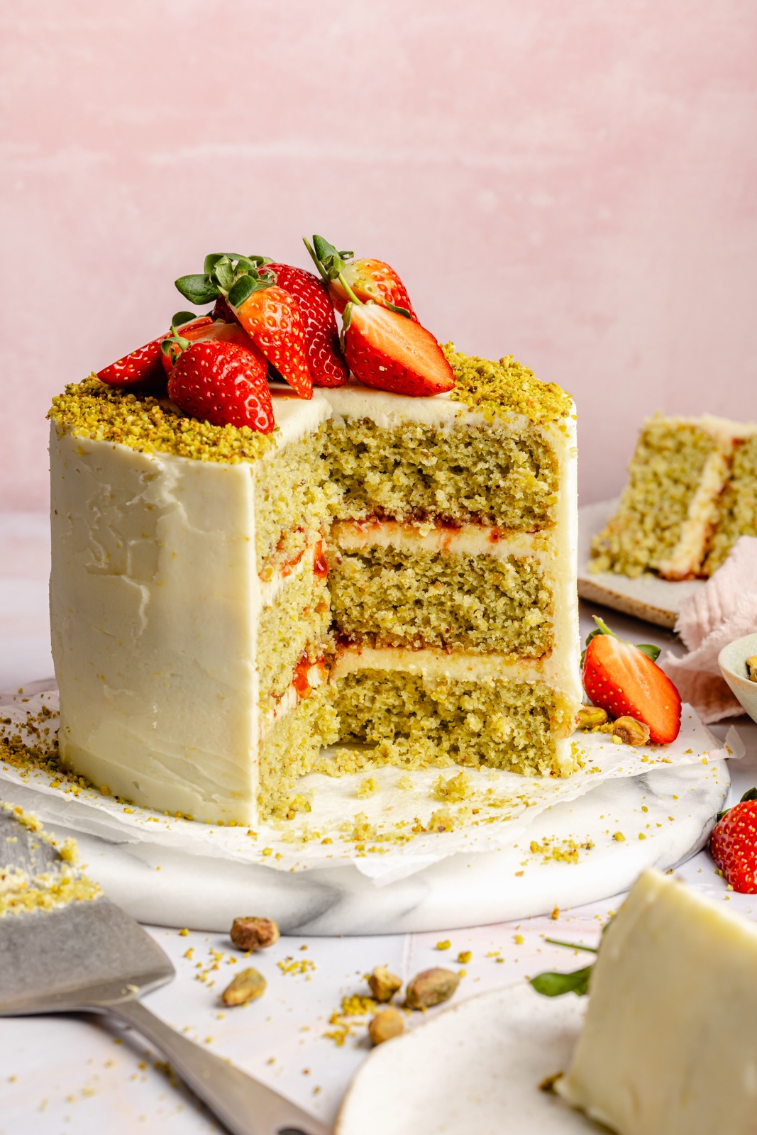 lemon pistachio cake topped with strawberries with slices cut out