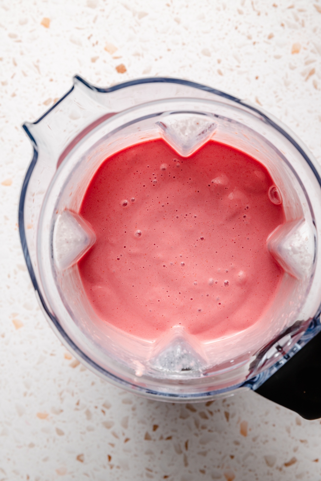 top-down view of a peach smoothie in a blender