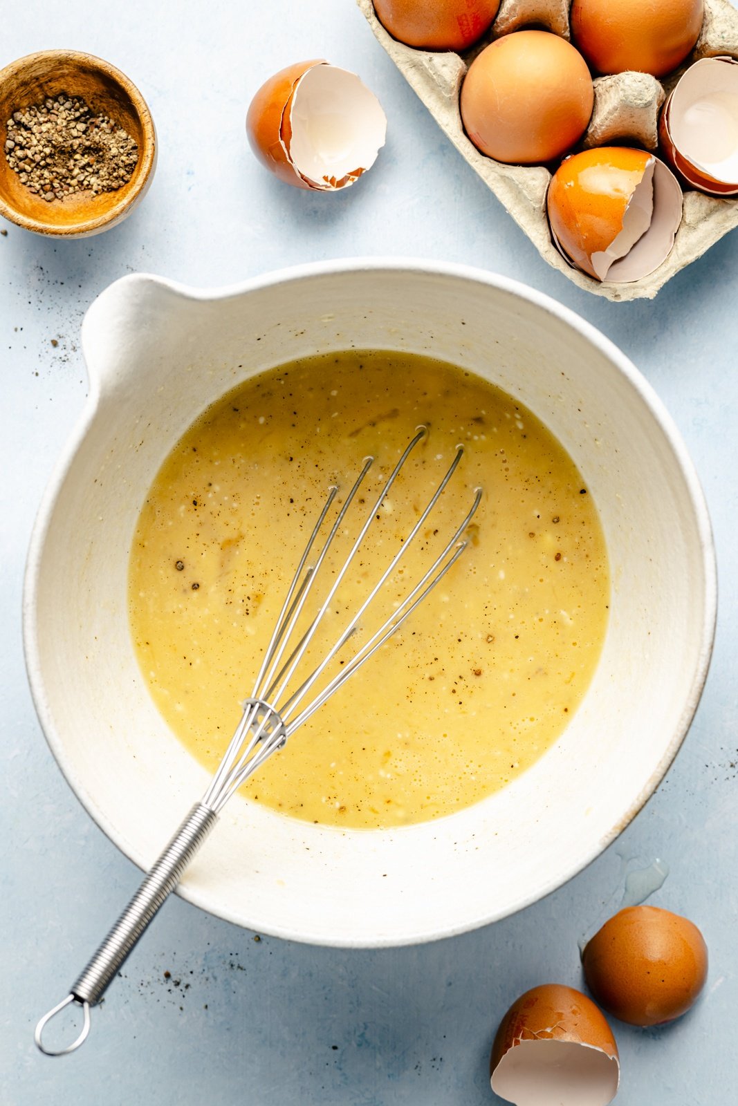 whisking eggs in a bowl for a spinach puff pastry quiche