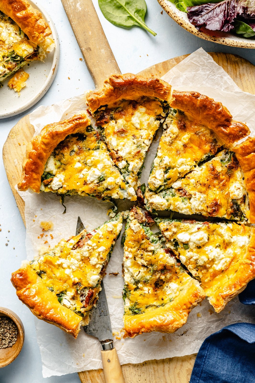 sun-dried tomato basil puff pastry quiche sliced on a wooden board