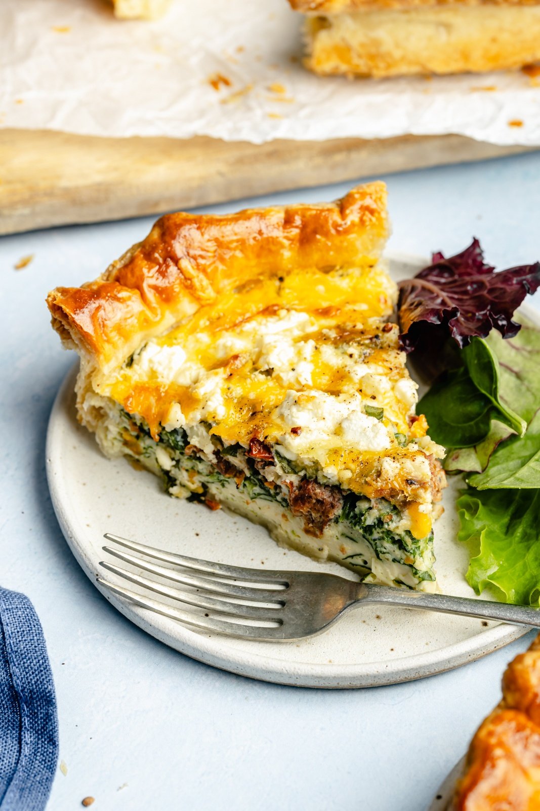 slice of spinach and sun-dried tomato puff pastry quiche on a plate