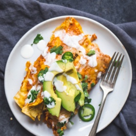 chicken pumpkin enchiladas on a plate topped with avocado