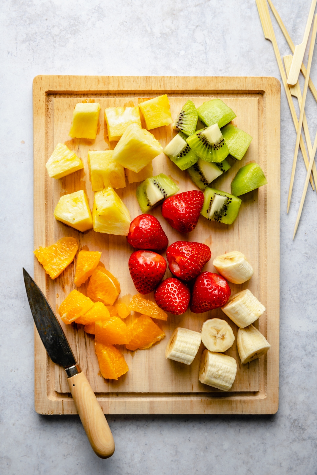 rainbow fruit for fruit kabobs on a cutting board