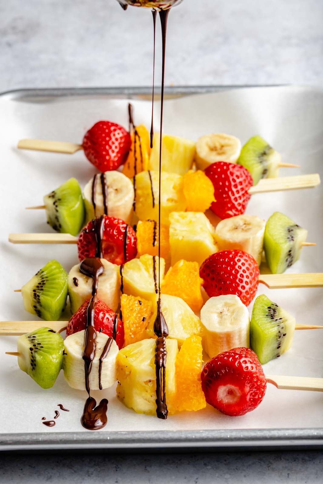 drizzling fruit skewers with chocolate