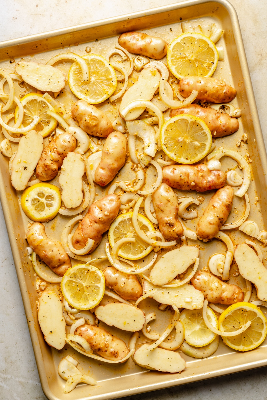 potatoes and lemons on a sheet pan before roasting