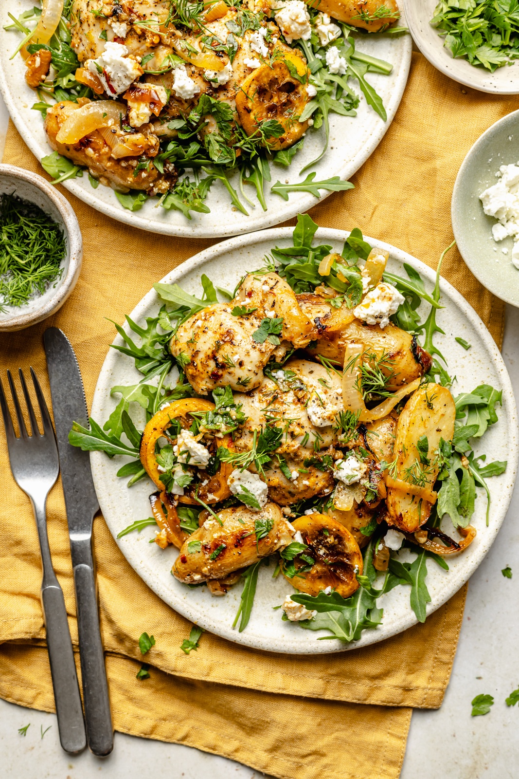 lemon garlic chicken and potatoes over a bed of arugula on a plate