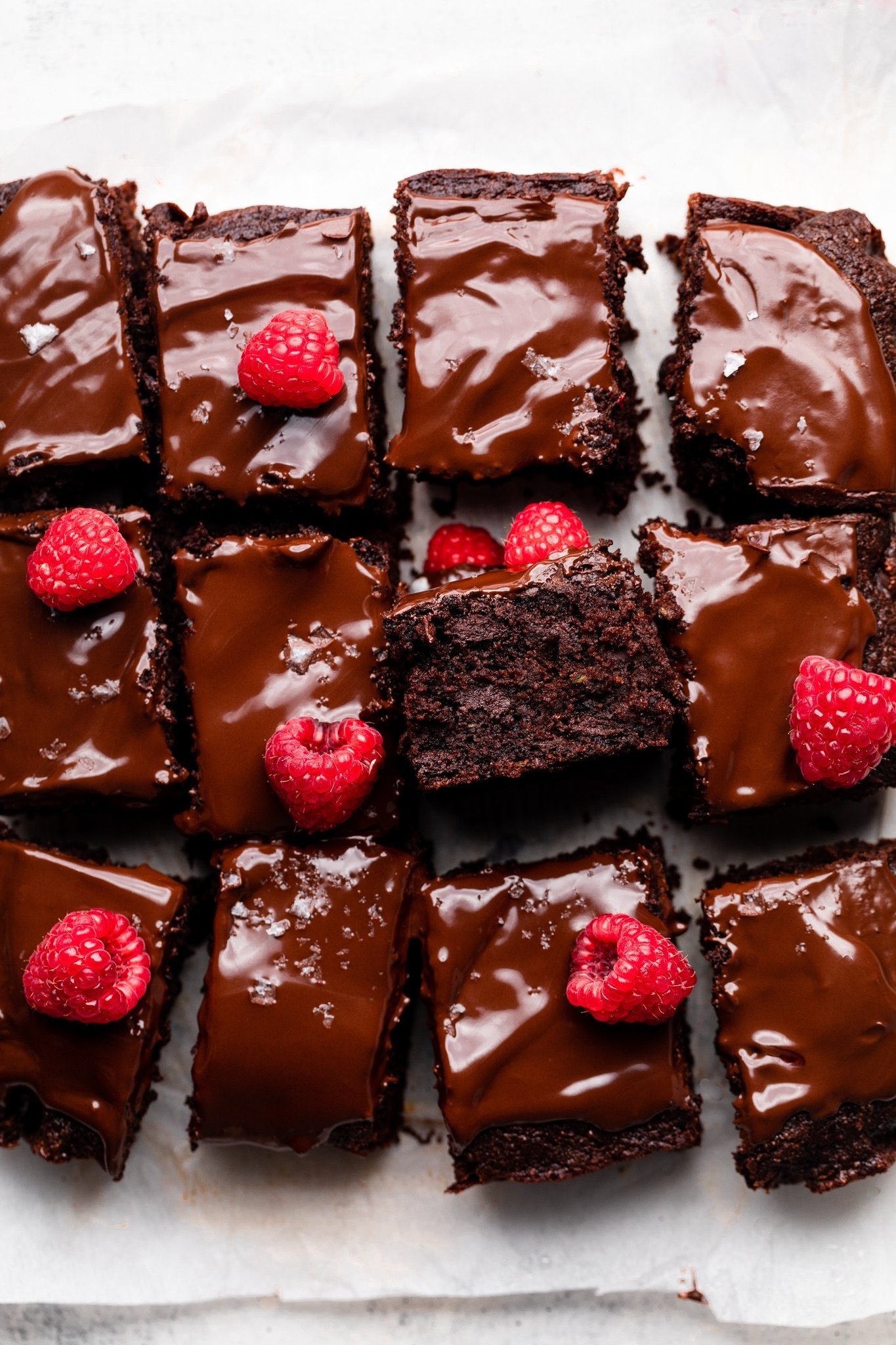 chocolate zucchini cake cut into squares and topped with raspberries