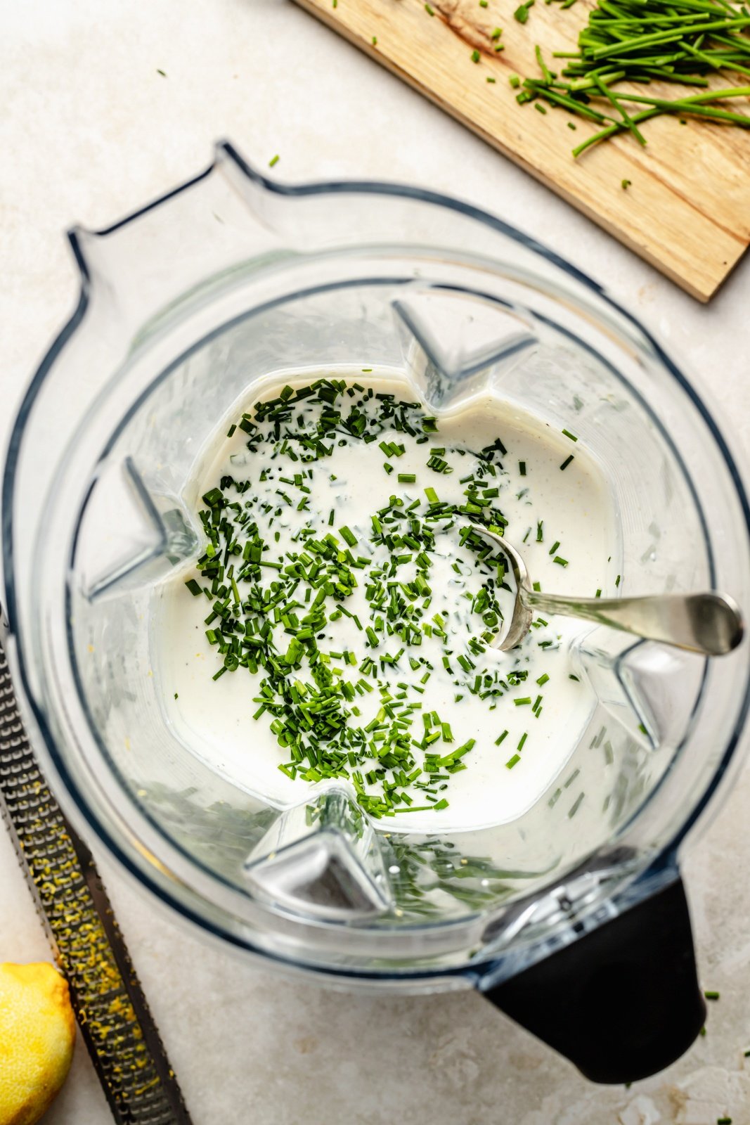 stirring chives into a blender with healthy sour cream and onion dip